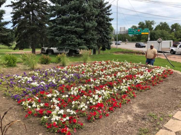 City Greenhouse Specialist John Berglund and the City's flag-in-flowers at the intersection of Omaha and West Boulevard.