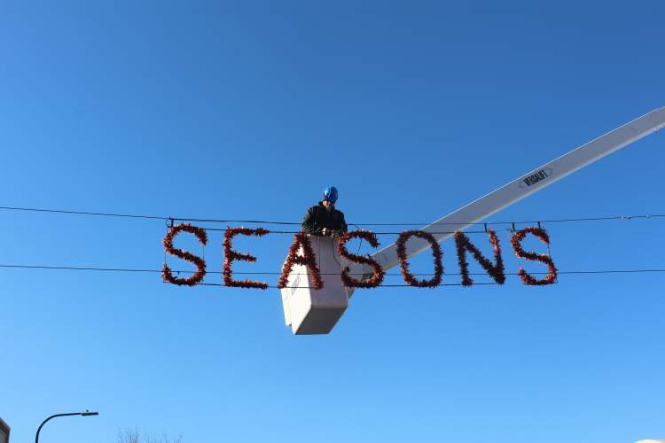 A member of the City Streets Department works on hanging a holiday banner across Main Street Tuesday, November 7.  Crews will be decorating the downtown corridor, Halley Park and Wilson Park.