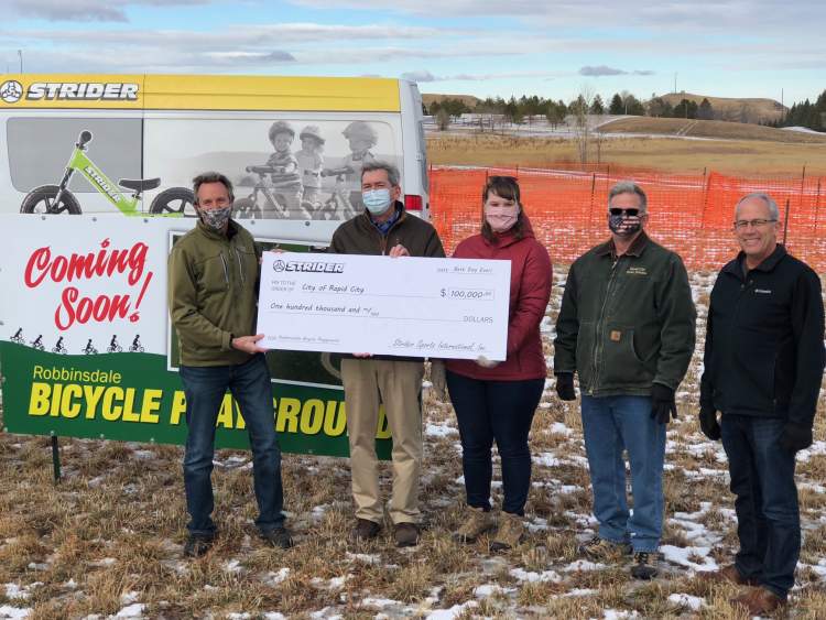 Strider Bikes CEO Ryan McFarland presents a $100,000 check to City Parks officials Jeff Biegler, Melissa Petersen and Scott Anderson and Mayor Steve Allender for development of a bicycle playground at Robbinsdale Park.