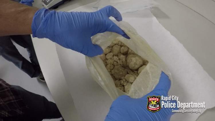 A member of UNET holds open a baggie containing heroin